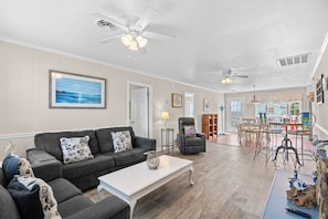 A spacious living room with a grey sofa, a white coffee table, and a dining area with metal chairs. - Waterfront Retreat 1 Block from the Beach Sleeps 8 (North Myrtle Beach)