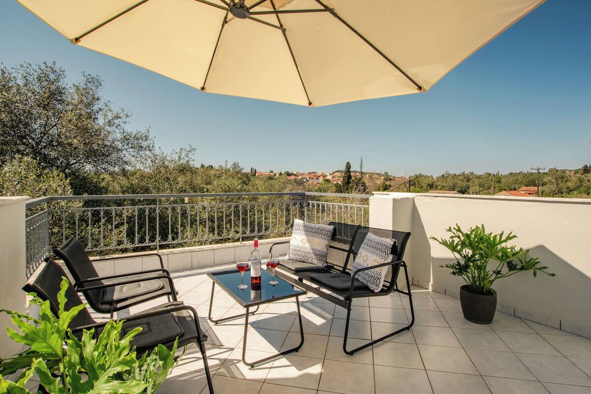 A terrace with a table, chairs, and a potted plant.