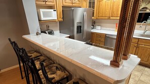 A kitchen with a marble countertop, wooden cabinets, a refrigerator, and a microwave. - Spacious and comfortable 3-bedroom house in peaceful Somerset, KY. All amenities (Somerset)