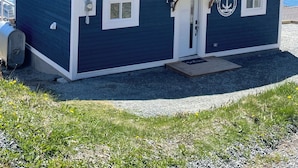 Ett litet, mörkblått hus med vita detaljer, en skorsten och en dörr prydd med ett runt emblem.