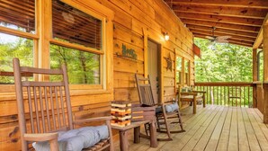 Eine Holzhütte mit einer Veranda, Holzstühlen und einem Stapel Holzklötze.