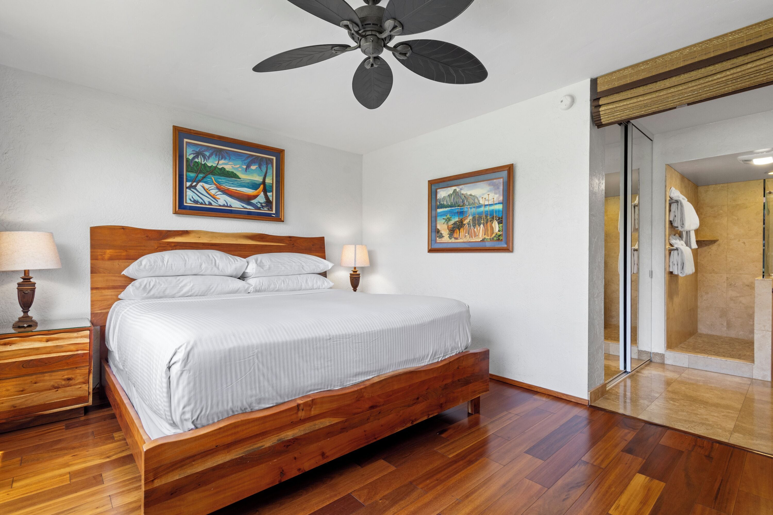 Une chambre à coucher avec un lit en bois, deux lampes fixées au mur et deux tableaux encadrés.