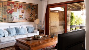 A living room with a sofa, coffee table, and artwork. - Casa Acqua e Pietra by Wonderful Italy (Golfo Aranci)