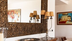 A wooden console table with a large ornate mirror, a lamp, and a decorative bowl. - Casa Acqua e Pietra by Wonderful Italy (Golfo Aranci)