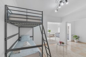 Un lit superposé avec une échelle, une petite table avec une plante et une vue sur un coin repas.