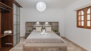 A bedroom with a bed, a wardrobe, a nightstand, and a window.