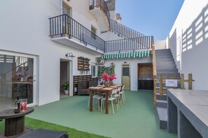 Une cour comprenant une table à manger, des chaises, un banc et un escalier.