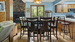 A dining area with a stone wall, a fireplace, and a large window. - Pet Friendly, Private Wooded Setting - Travelers Rest by Carolina Properties (Rutherfordton)