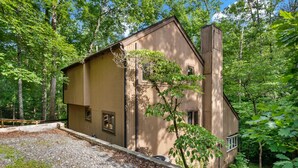 A wooden cabin with a sloped roof, surrounded by dense forest. - Pet Friendly, Private Wooded Setting - Travelers Rest by Carolina Properties (Rutherfordton)