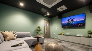 Un salon moderne avec un canapé gris, une petite table ronde et un téléviseur fixé au mur.