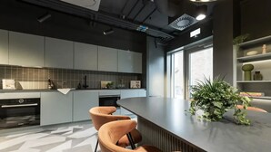 Une cuisine moderne avec des meubles gris, un îlot central doté de tabourets et une plante en pot.