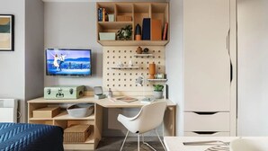 Une chambre à coucher moderne, comprenant un lit, un bureau avec une chaise, une télévision et une armoire.