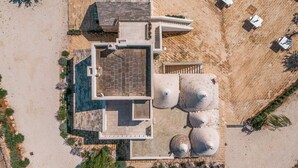 An aerial view of a property with a swimming pool, multiple large water tanks, and a patio area with outdoor seating.