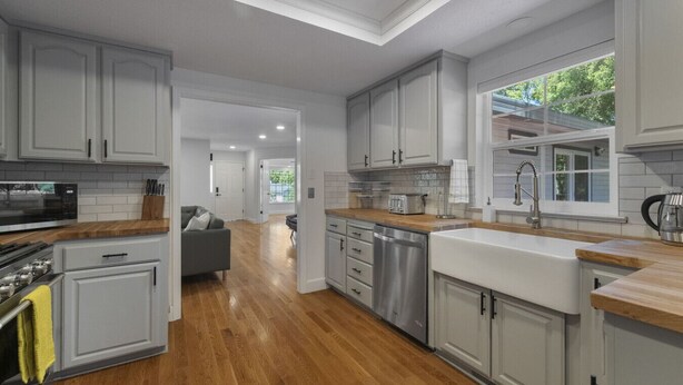 Una cocina moderna con armarios blancos, piso de madera y vistas al exterior.