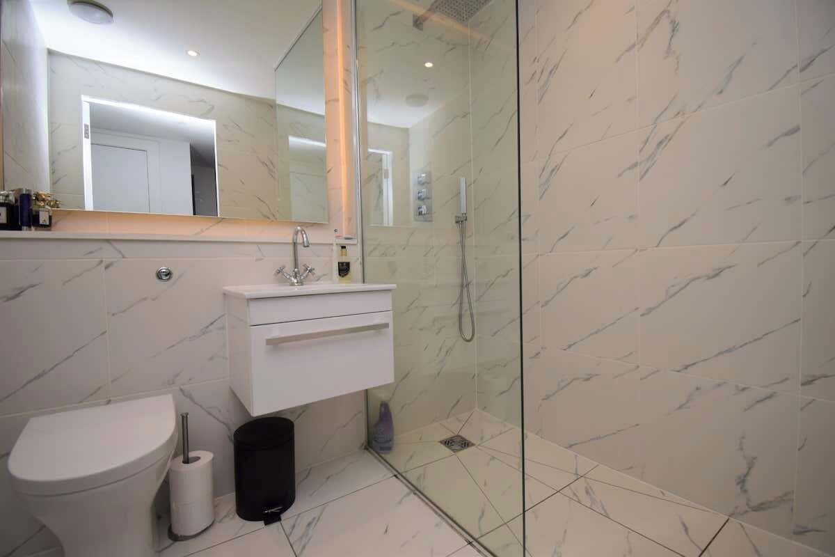 A modern bathroom with a toilet, sink, and glass shower enclosure.