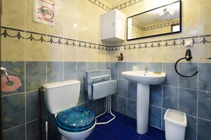 Een badkamer met toilet, wastafel en spiegel.