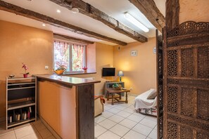 A room with a wooden ceiling, a window with a view, a television, a table with a lamp, and a bed. - Holiday Home 'La Charrue' with Mountain View, Shared Pool and Wi-Fi (Villecomtal)