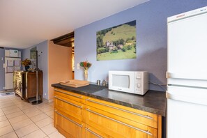 A kitchen with a microwave, wooden cabinets, a sink, and a framed picture on the wall.