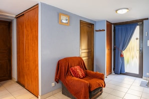 A room with a wooden door, a blue wall, a red chair with a cushion, and a blue curtain.