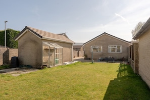 Stroll through the beautifully maintained lawn to the charming brick house with a greenhouse for gardening and a driveway.