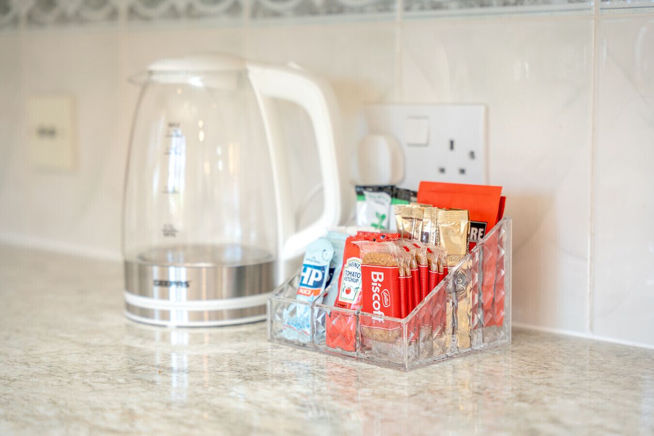 A kitchen counter with a coffee maker, a glass container, and a spice rack with various condiments.