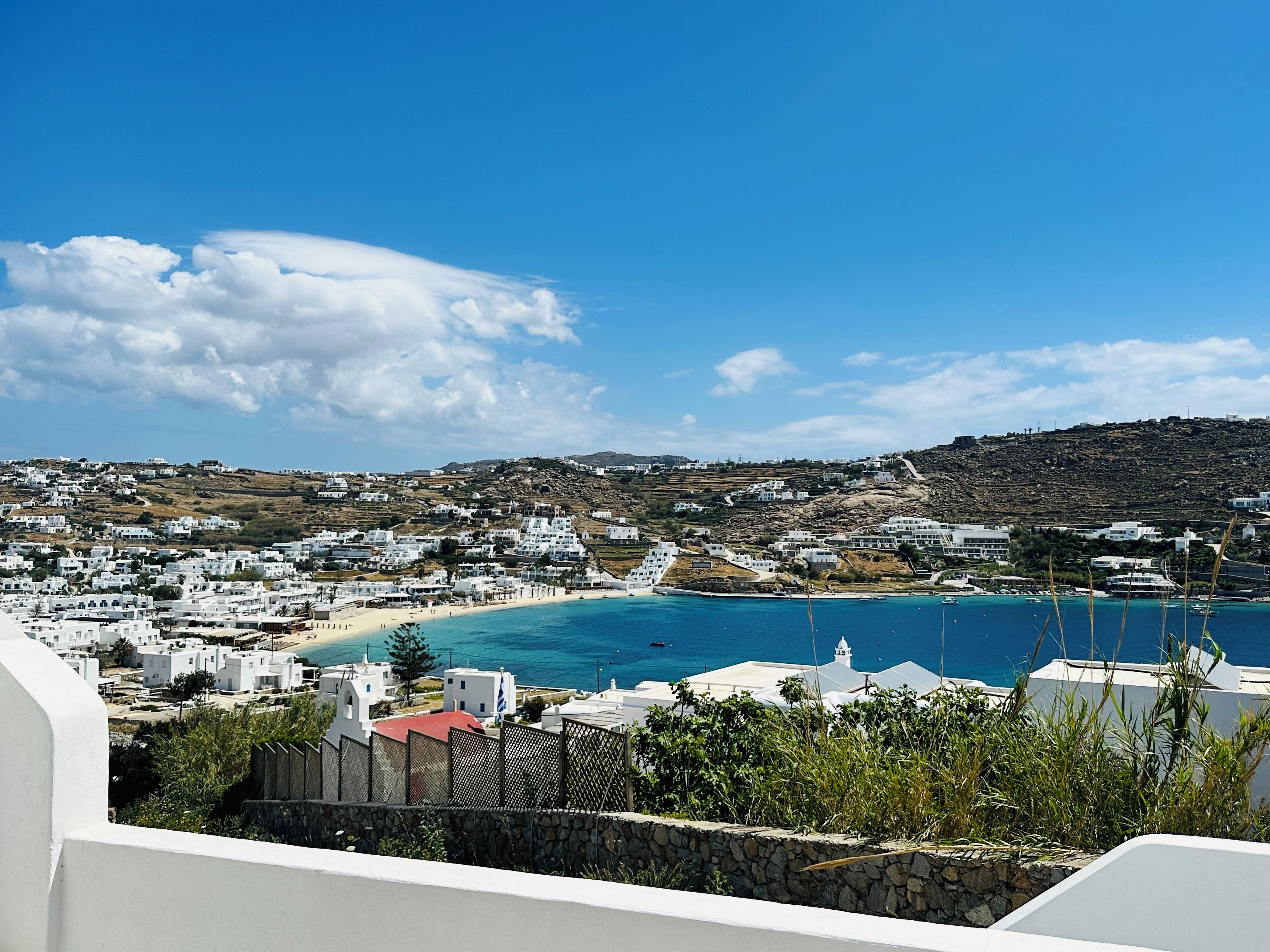 Un pueblo costero con edificios blancos, una playa y un cielo azul despejado.