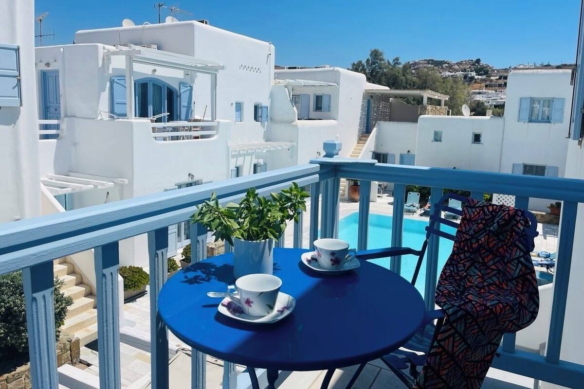 A balcony with a table, two cups, and a plant.