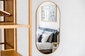 A bedroom with a bed, pillows, a bedside table, and a mirror reflecting the room. - Apartment 'De Gasperi' with Balcony, Wi-Fi and Air Conditioning (Bari)
