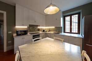 A modern kitchen with white cabinets, a marble countertop, and a large window.
