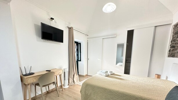Een moderne hotelkamer met een bed, een bureau met stoel, een flatscreen televisie en een groot raam.