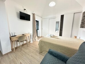Une chambre d’hôtel moderne équipée d’un lit, d’un bureau avec une chaise, d’un téléviseur à écran plat et d’une grande fenêtre.