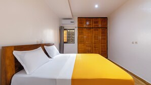 Une chambre à coucher avec un lit en bois, une literie blanche et jaune, une armoire en bois et une fenêtre donnant sur un paysage agréable.