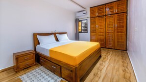 Une chambre à coucher avec un lit en bois, une table de chevet, une armoire et une fenêtre avec des rideaux.