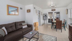 Een woonkamer met een bruine leren bank, een salontafel, en een eethoek met houten stoelen en een tafel.