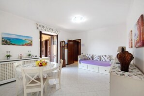 A room with a dining table, chairs, a sofa, a bed, and a large vase. - Apartment 'La Terrazza Di Basilio' with Lake View, Balcony and Wi-Fi (Olginate)