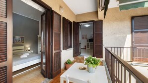 A balcony with a table, chairs, a potted plant, and a view of the adjacent room. - Apartment 'La Terrazza Di Basilio' with Lake View, Balcony and Wi-Fi (Olginate)