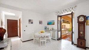 A dining area with a table and chairs, a clock, and a door leading to another room. - Apartment 'La Terrazza Di Basilio' with Lake View, Balcony and Wi-Fi (Olginate)