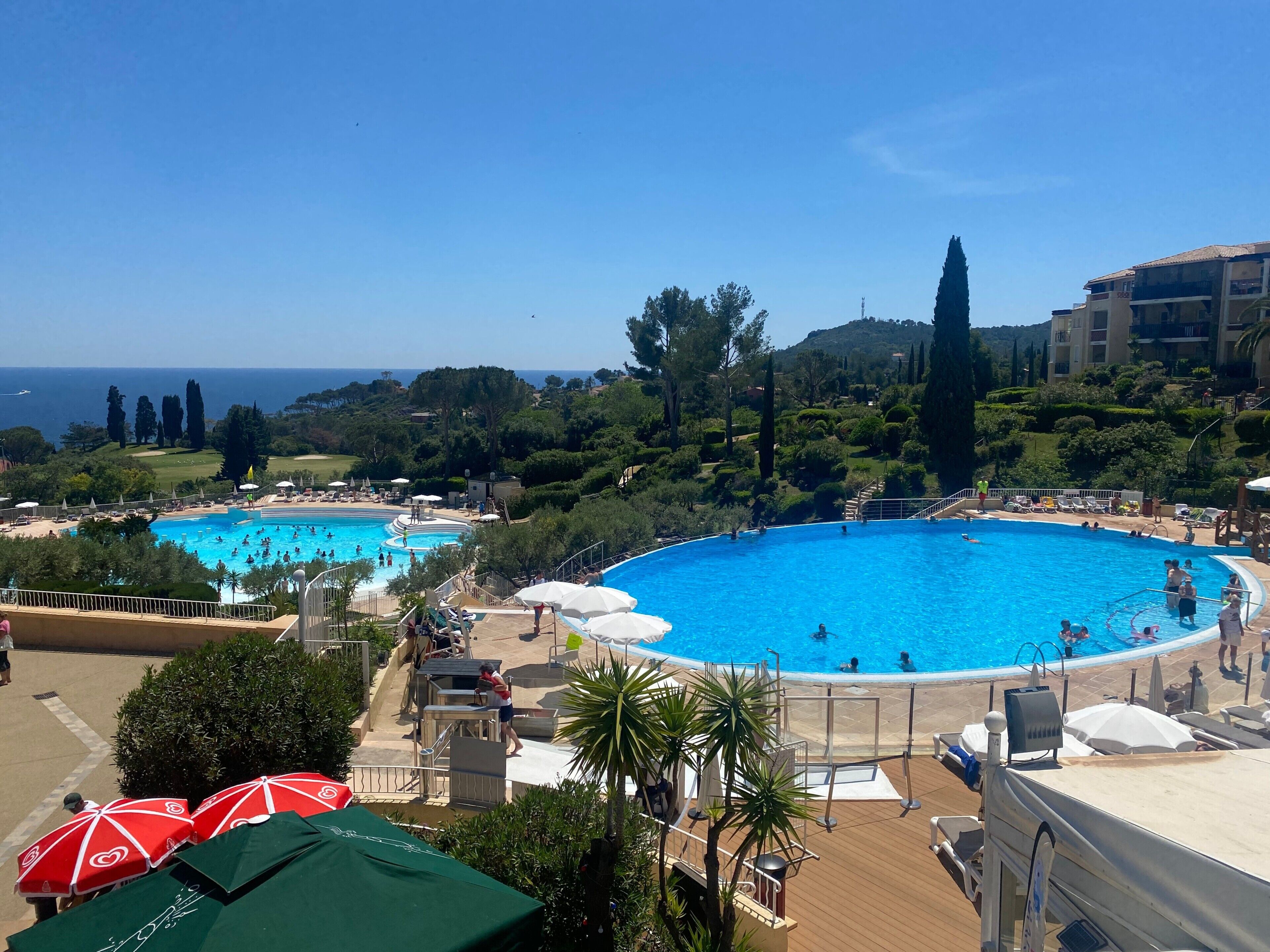 Un resort con due piscine, lettini e vista sul mare.
