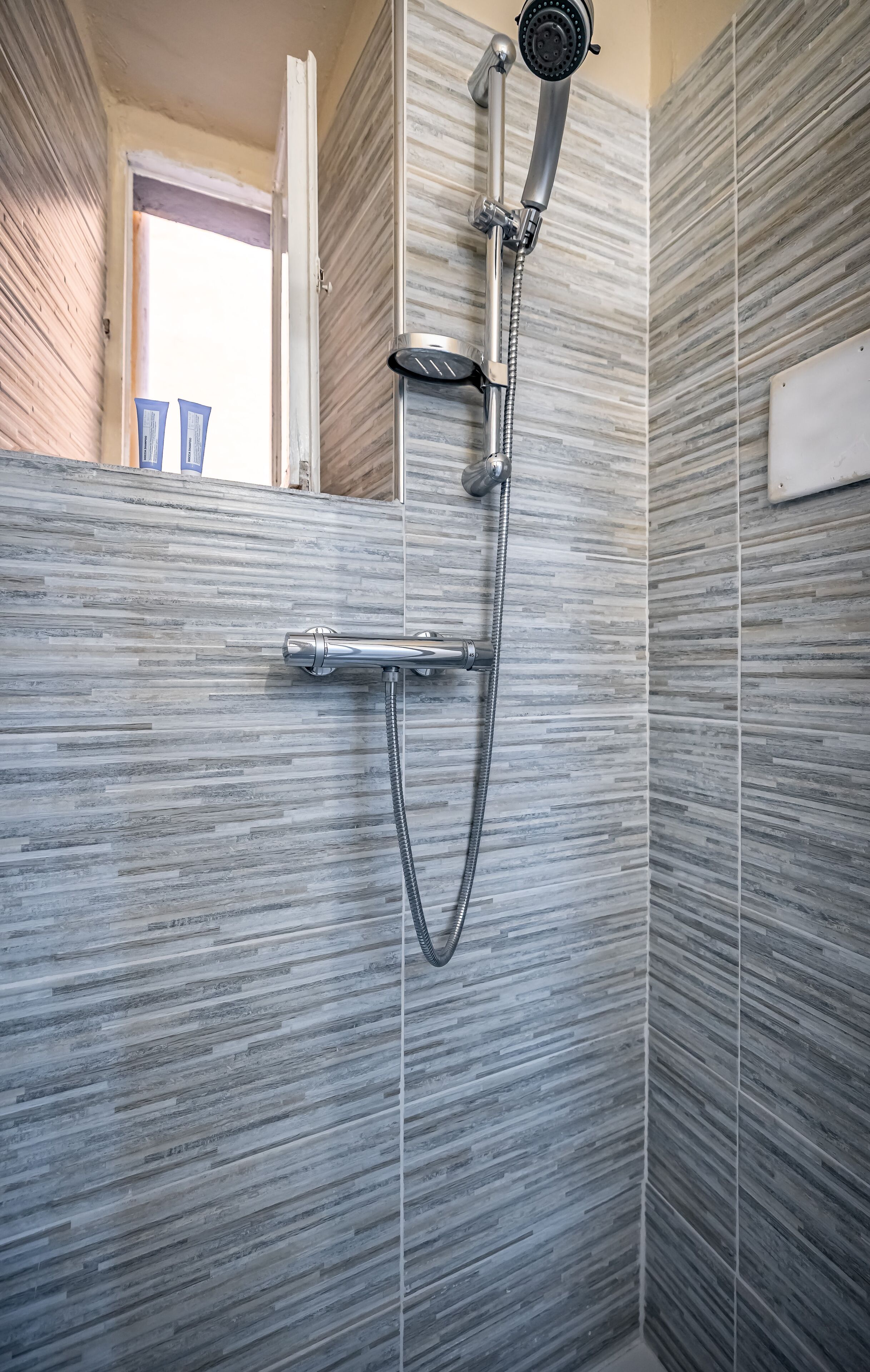 A shower with a handheld showerhead and a handheld hose.