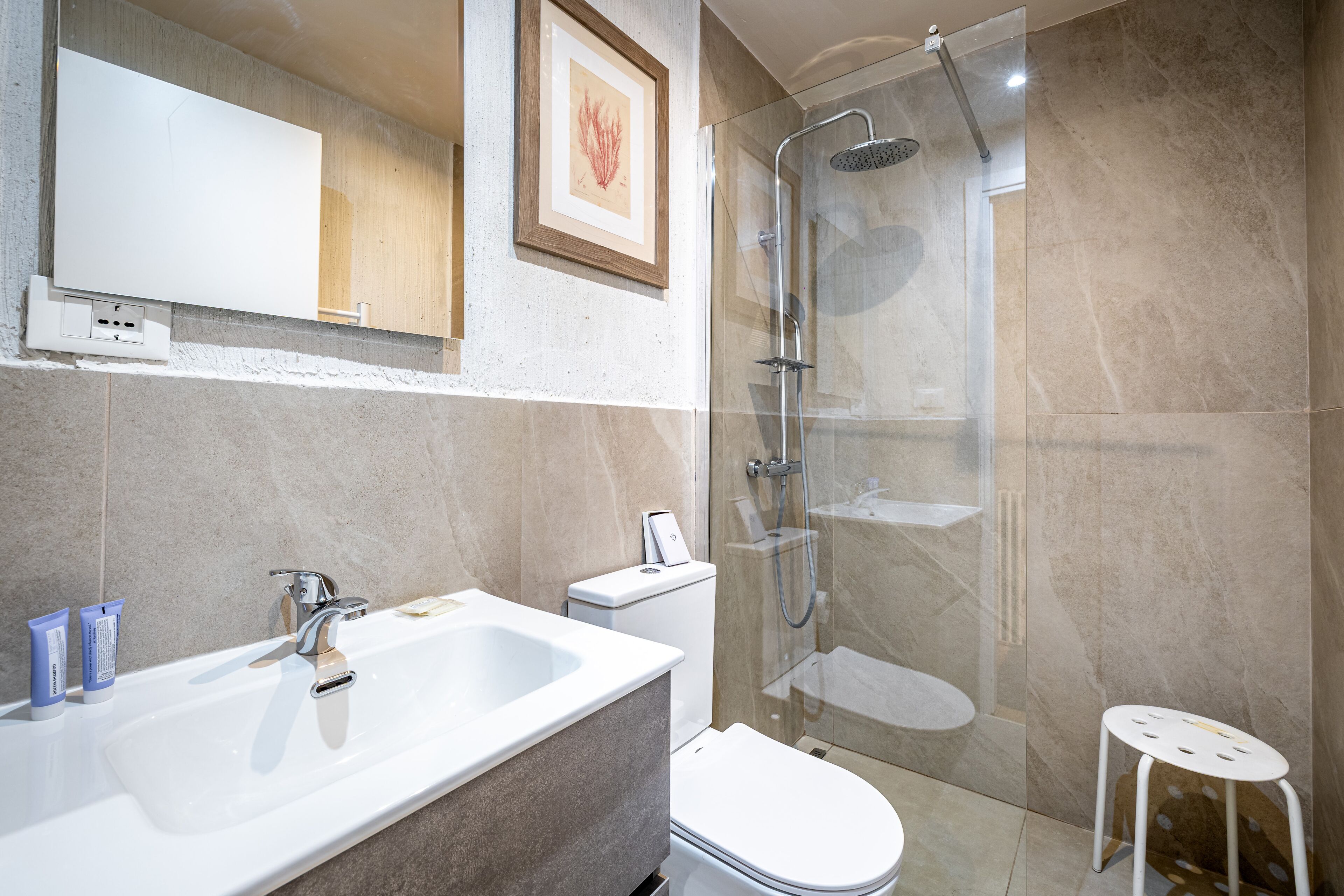 A modern bathroom with a large sink, toilet, and glass-enclosed shower.