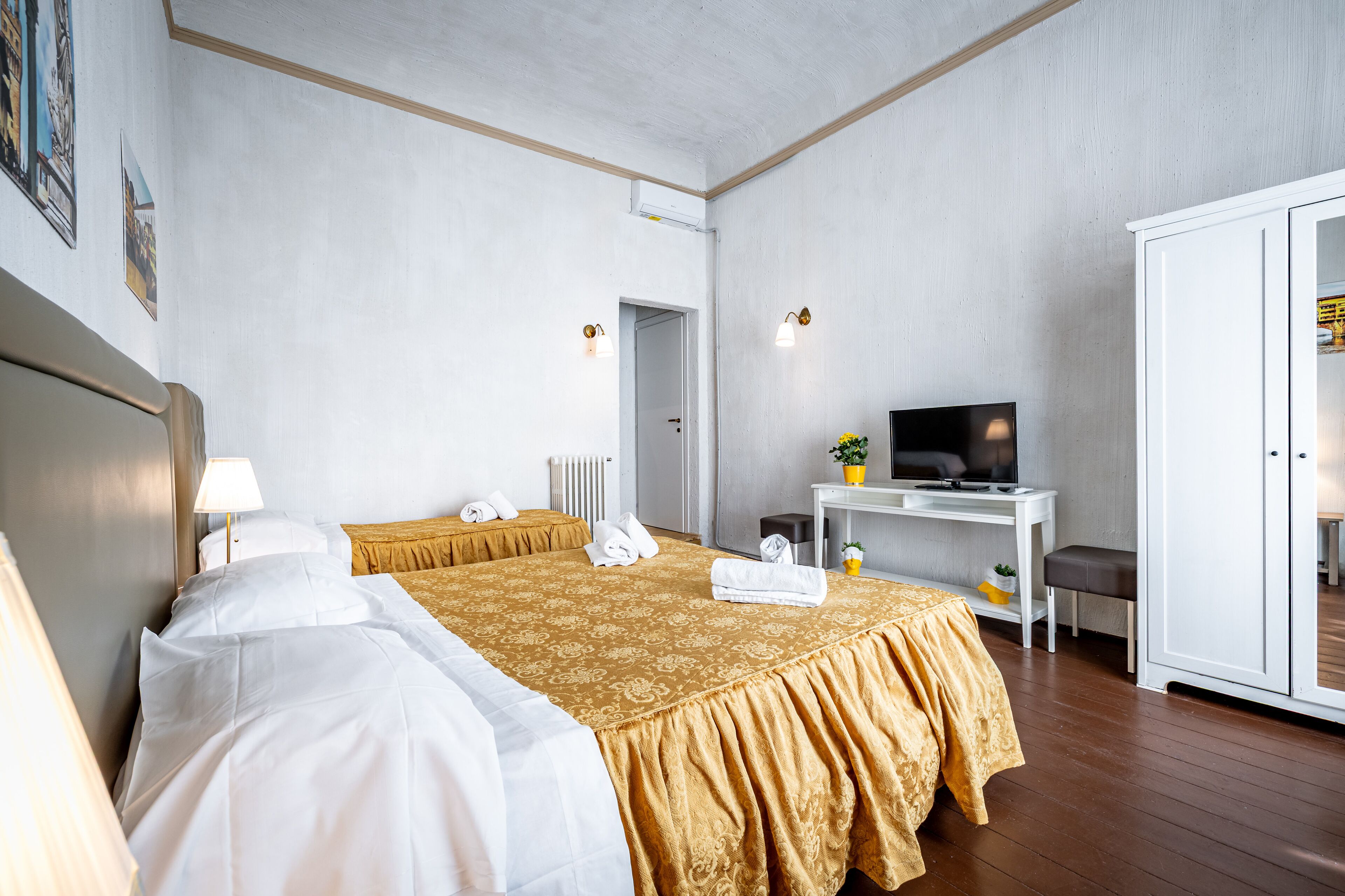 A hotel room with two beds, a desk with a TV, and a wardrobe.