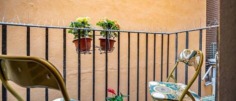 Un balcon avec deux chaises et deux plantes en pot.