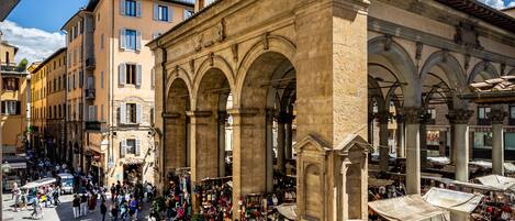 A historic square with a central open space surrounded by buildings with arches and columns.