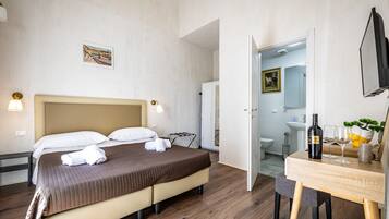 Una camera d'albergo con un letto, un comodino e vista sul bagno.