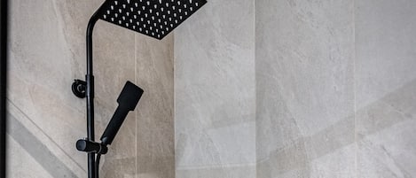 Una ducha moderna con cabezal de ducha manual y otro fijo en la pared.