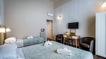 Ein Hotelzimmer mit zwei Betten, einem Schreibtisch mit Stuhl, einem Fernseher und einer Heizung.