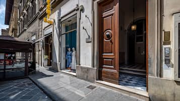 Vista de la calle de un edificio con puerta de madera, una tienda con maniquíes y un letrero que dice