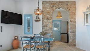 Comedor con suelo de piedra, una mesa y sillas, una lámpara colgante y un arco de pared de piedra.
