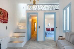 Escadaria que leva a um quarto com uma cama, um sofá e um objeto decorativo na parede.