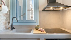 Una cocina con un lavabo, estufa, armario azul y una campana extractora moderna.